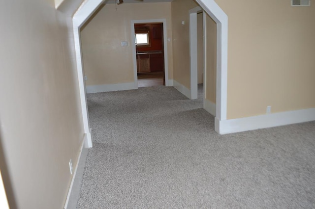 corridor with light colored carpet and vaulted ceiling