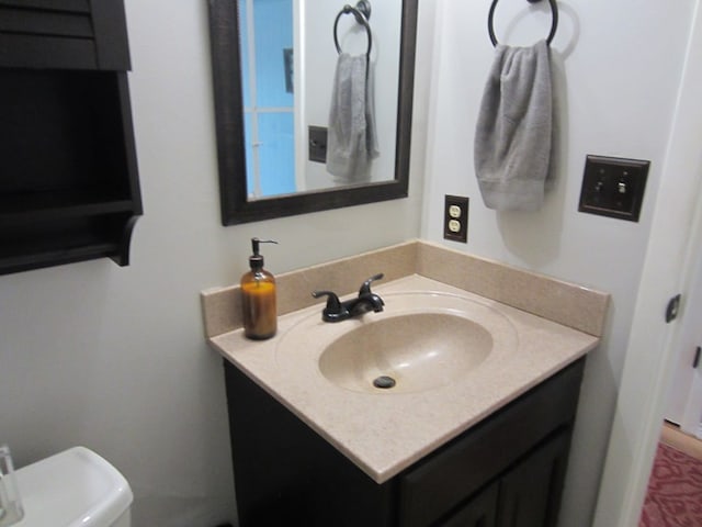 half bath featuring vanity and toilet