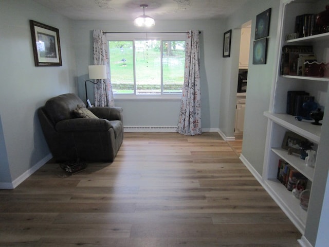 living area featuring a baseboard heating unit, baseboards, and light wood finished floors