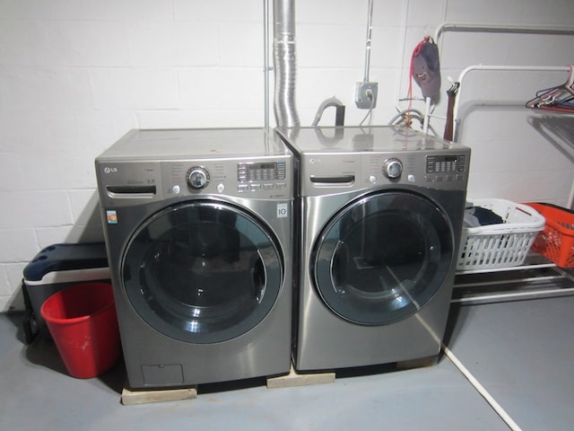 laundry room featuring laundry area, washer and clothes dryer, and concrete block wall