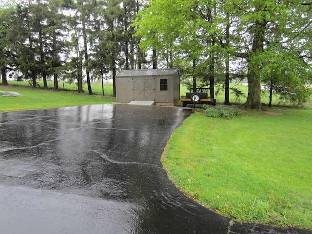 exterior space featuring a front yard, an outbuilding, a shed, and aphalt driveway