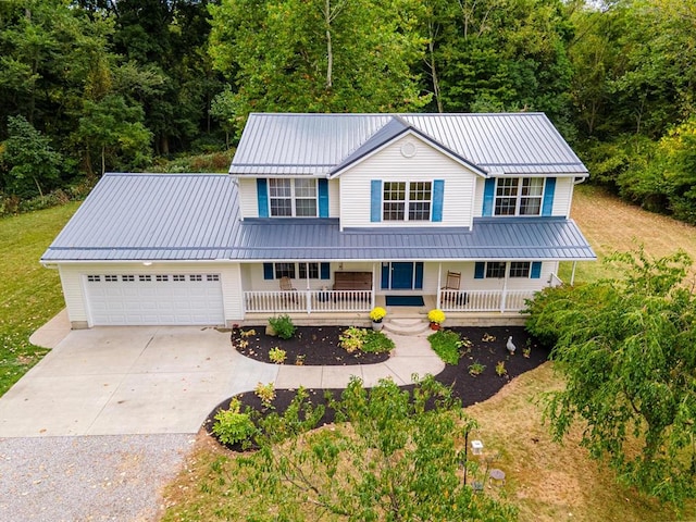 view of front of property featuring covered porch, a garage, and a front lawn