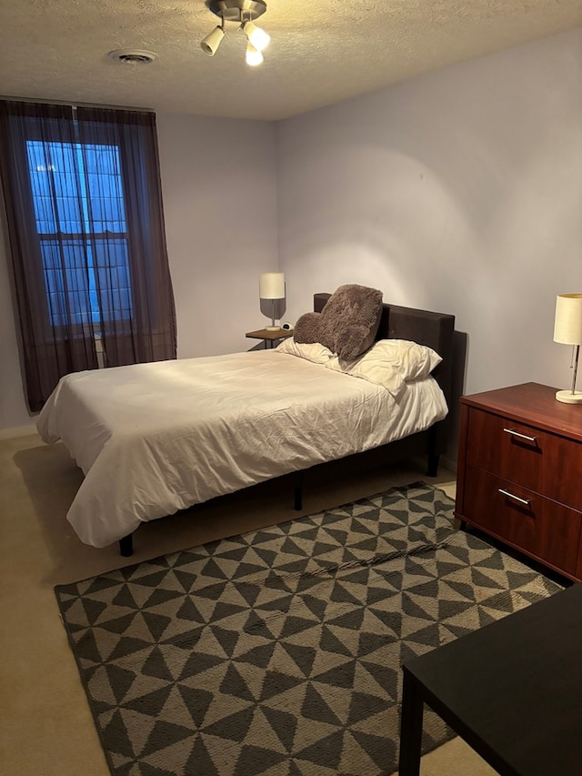 bedroom featuring carpet flooring, visible vents, and a textured ceiling