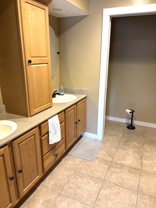 bathroom featuring tile patterned flooring, double vanity, baseboards, and a sink