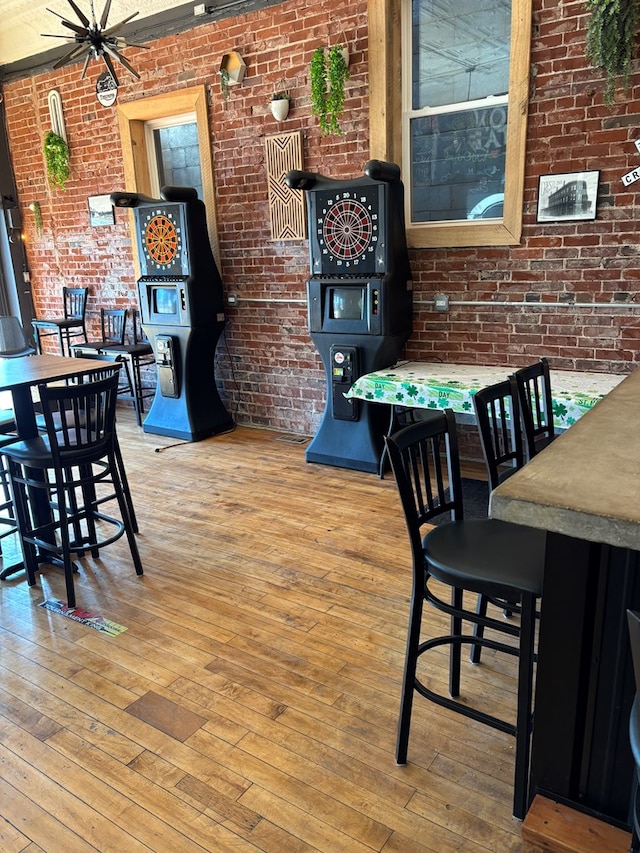 dining space featuring a wood stove, wood-type flooring, and brick wall