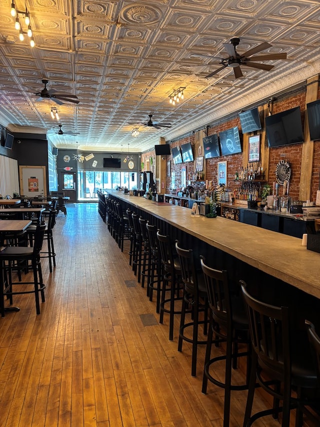 bar with a dry bar, an ornate ceiling, ceiling fan, and hardwood / wood-style flooring