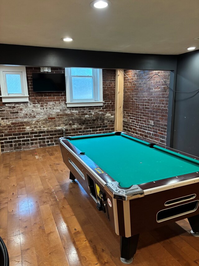 game room with a healthy amount of sunlight, brick wall, and hardwood / wood-style flooring