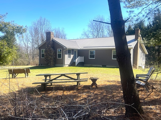 rear view of property with metal roof, crawl space, a chimney, and a lawn