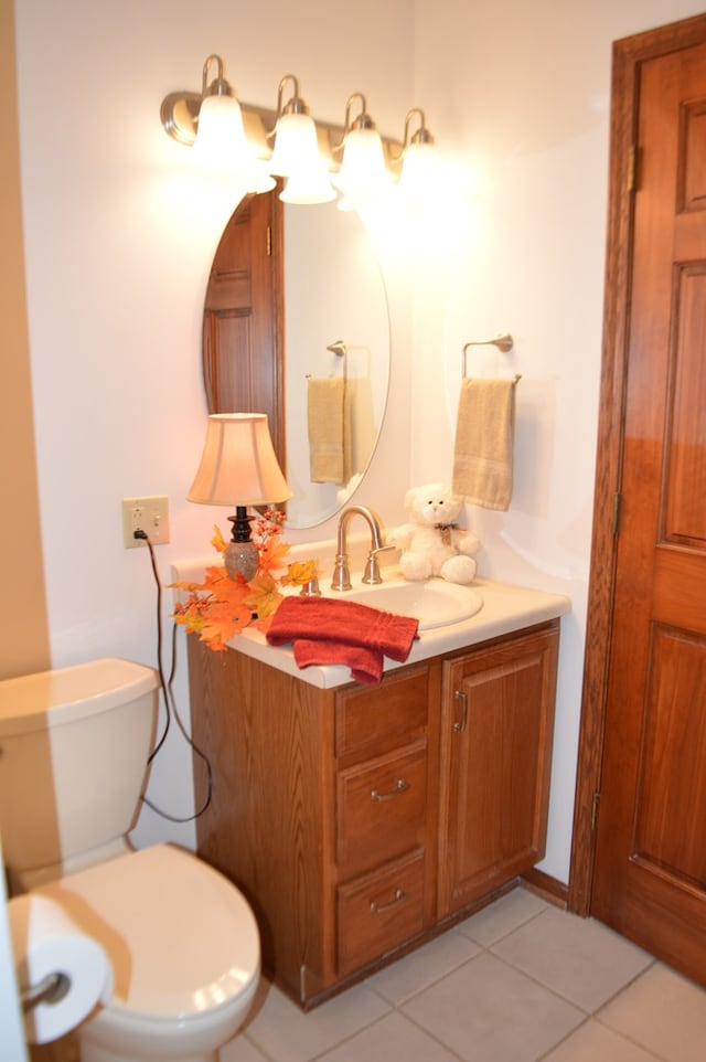 bathroom with toilet, vanity, and tile patterned floors