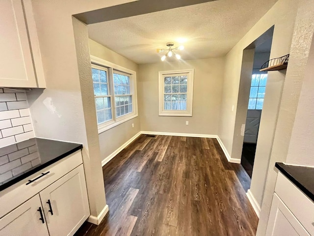 114 Avalon Rd, Mount Vernon, OH 43050 - unfurnished dining area with dark wood-style flooring, plenty of natural light, baseboards, a textured ceiling, and a chandelier