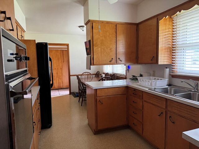 763 Sunnyside Dr, Galion, OH 44833 - kitchen featuring a peninsula, healthy amount of natural light, light countertops, and freestanding refrigerator