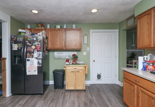 kitchen featuring stainless steel fridge, wood-type flooring, and a textured ceiling