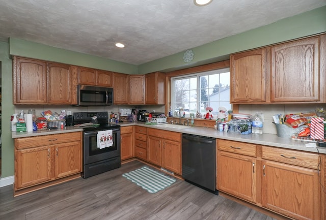 kitchen featuring a textured ceiling, sink, dark wood-type flooring, and black appliances