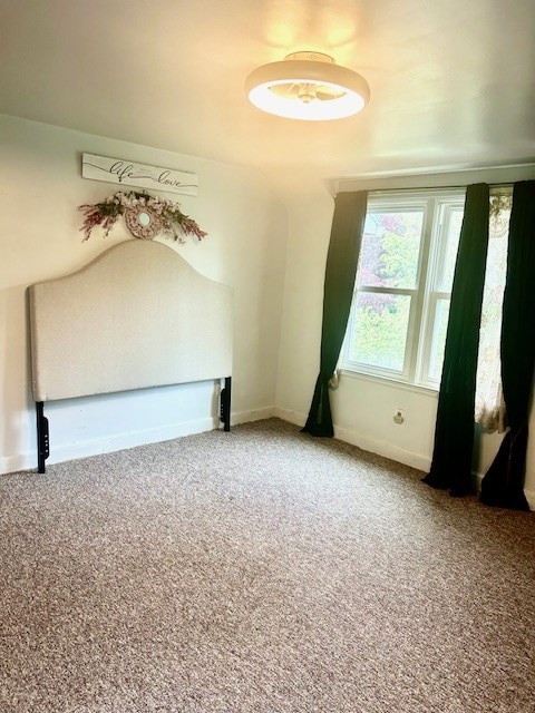 spare room with baseboards and carpet