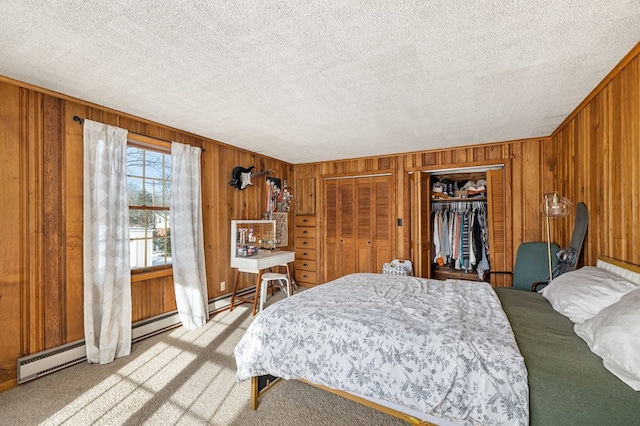 bedroom featuring two closets, wooden walls, light carpet, and a textured ceiling