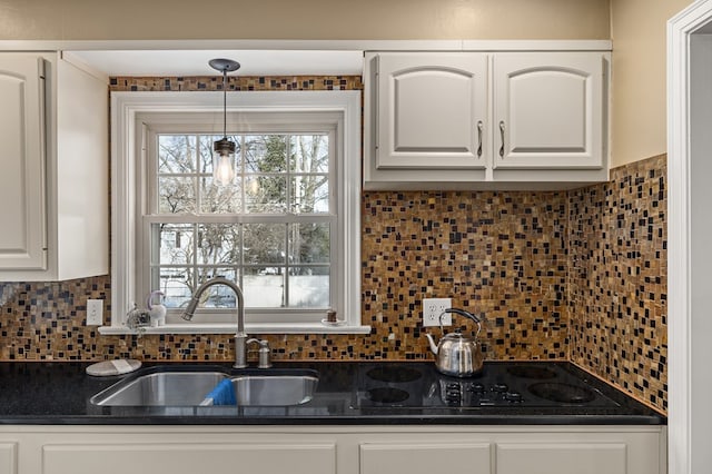 kitchen featuring sink, decorative backsplash, hanging light fixtures, and white cabinets