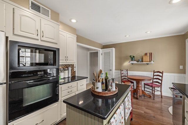 kitchen featuring dark wood-type flooring, white cabinetry, a center island, tasteful backsplash, and black appliances