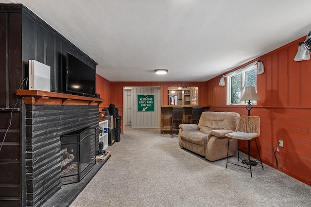 living room featuring wood walls, a fireplace, carpet, and a textured ceiling