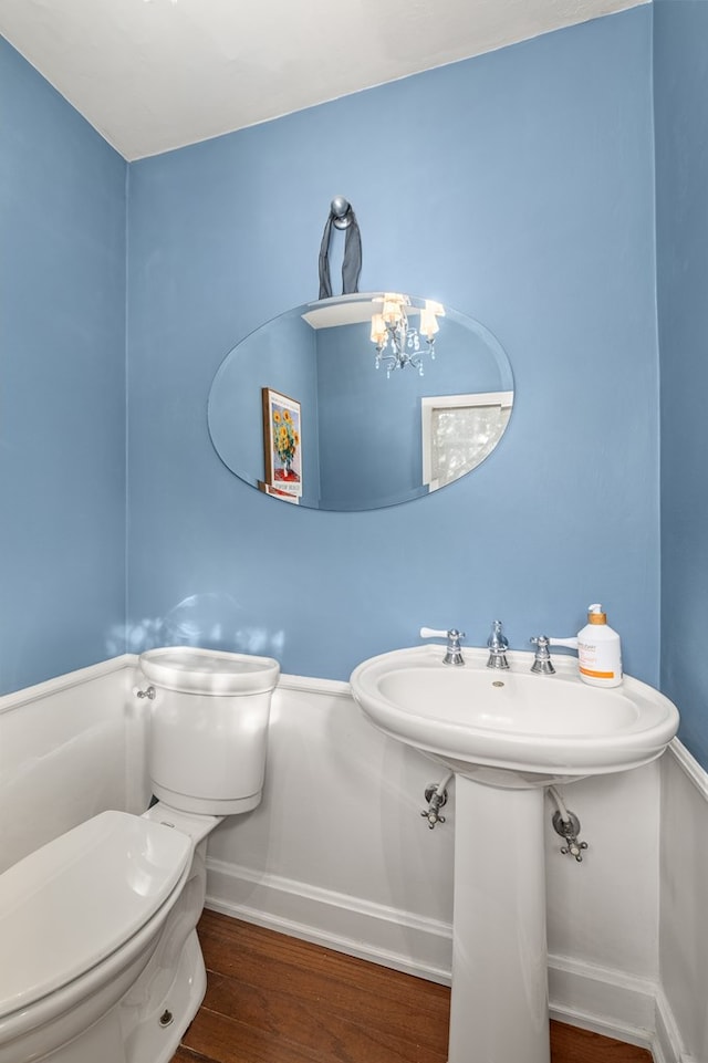 bathroom featuring wood-type flooring, a notable chandelier, and toilet