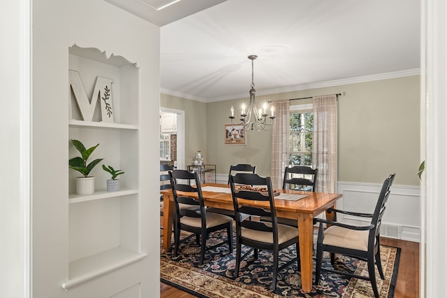 dining area featuring hardwood / wood-style flooring, crown molding, a notable chandelier, and built in features