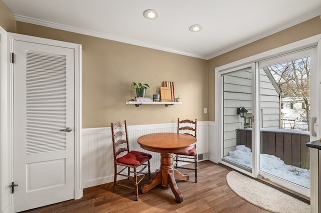 dining area with wood-type flooring and ornamental molding