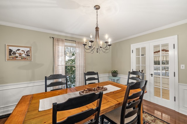 dining space with crown molding, wood-type flooring, a chandelier, and french doors