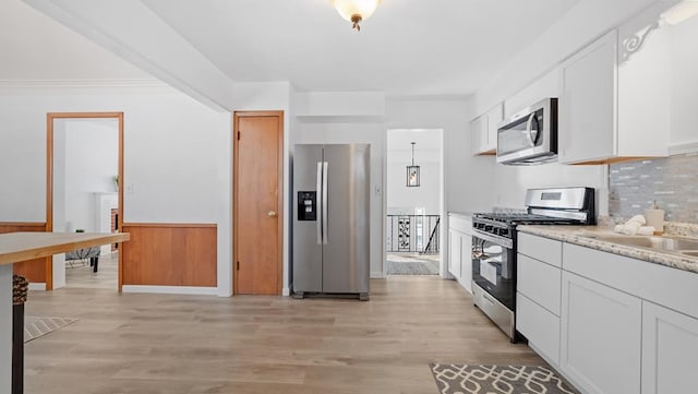 kitchen with decorative backsplash, light wood-type flooring, white cabinetry, and appliances with stainless steel finishes