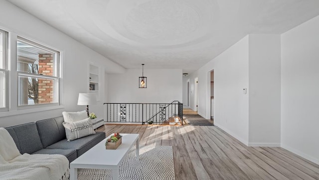 living room featuring light wood-type flooring, built in features, and baseboard heating