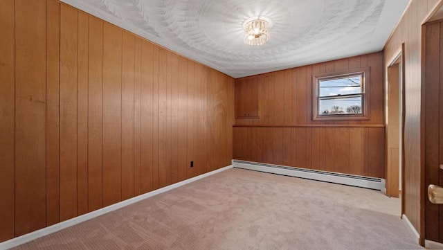 carpeted spare room with ornamental molding, wooden walls, and a baseboard heating unit