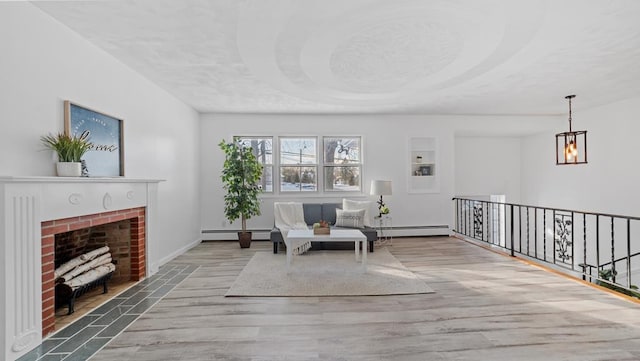 living area featuring a notable chandelier, light hardwood / wood-style floors, a fireplace, and a baseboard radiator