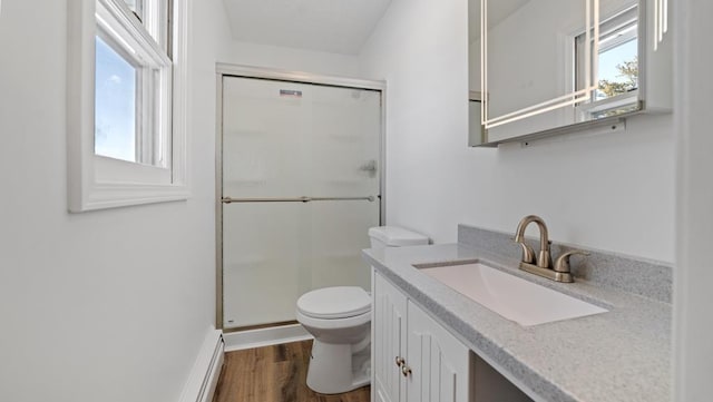 bathroom featuring baseboard heating, an enclosed shower, toilet, vanity, and hardwood / wood-style flooring