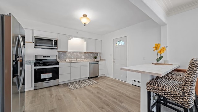 kitchen with backsplash, a baseboard heating unit, light hardwood / wood-style flooring, white cabinetry, and stainless steel appliances