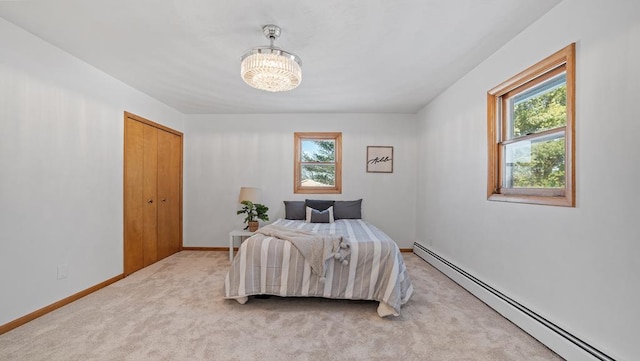 carpeted bedroom with a chandelier, a closet, and a baseboard radiator