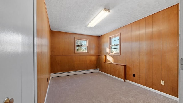 carpeted spare room featuring wood walls and a baseboard radiator