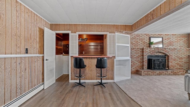 interior space featuring carpet, wood walls, a wood stove, and baseboard heating