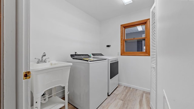 washroom featuring washer and dryer, light hardwood / wood-style flooring, and sink