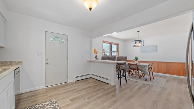 interior space featuring pendant lighting, dishwasher, white cabinets, light hardwood / wood-style flooring, and a baseboard radiator