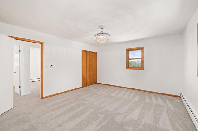 unfurnished room with a notable chandelier, light colored carpet, and a baseboard radiator