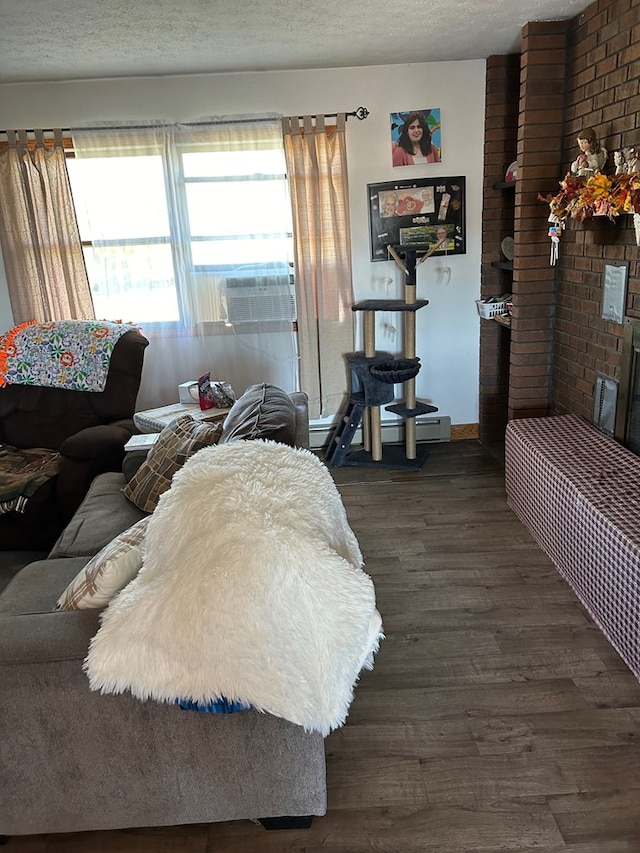 living room with a fireplace, cooling unit, dark wood-type flooring, and a textured ceiling