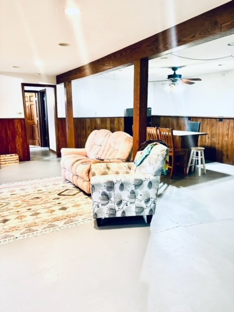 living room featuring beam ceiling, ceiling fan, and concrete flooring