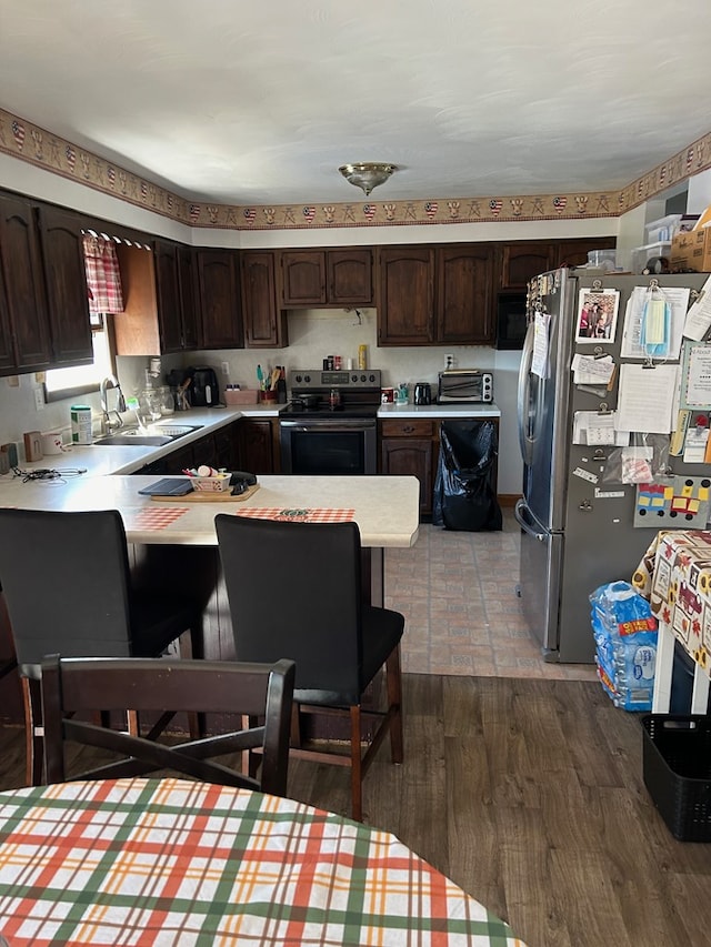 kitchen featuring kitchen peninsula, appliances with stainless steel finishes, dark brown cabinets, and sink