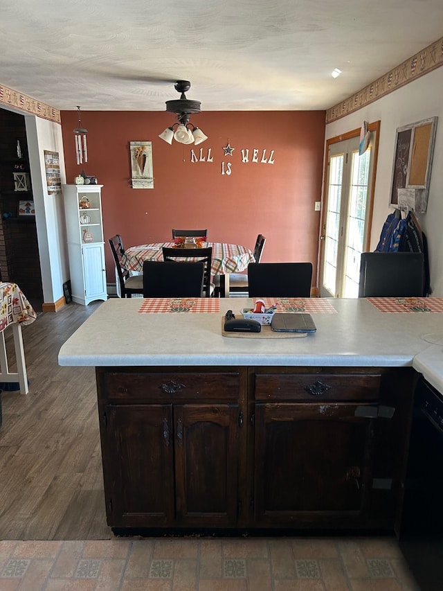 kitchen with dark wood-type flooring, ceiling fan, black dishwasher, dark brown cabinets, and kitchen peninsula