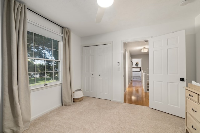 bedroom with a closet, ceiling fan, and light colored carpet