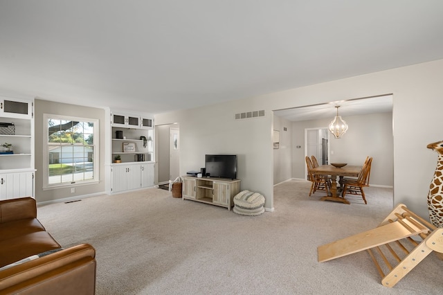 carpeted living room with a notable chandelier and built in shelves