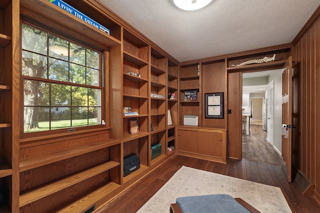 mudroom featuring a textured ceiling, wood walls, and dark wood-type flooring