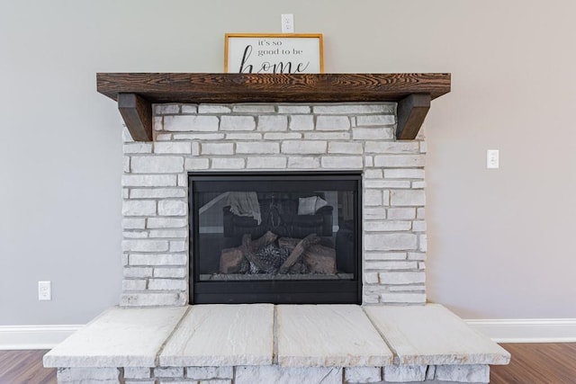 interior details with wood-type flooring and a brick fireplace