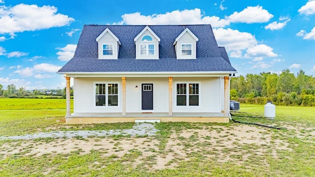 cape cod-style house featuring central AC unit, covered porch, and a front lawn