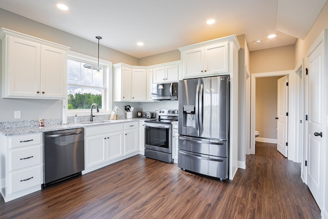 kitchen with appliances with stainless steel finishes, decorative light fixtures, sink, white cabinets, and light stone countertops