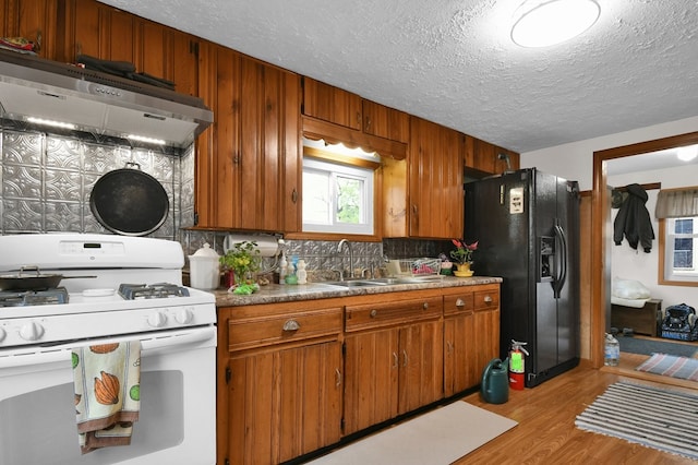 28 W Main St, Hayesville, OH 44838 - kitchen with black refrigerator with ice dispenser, a sink, white gas range oven, extractor fan, and brown cabinets