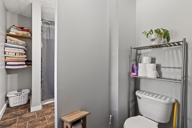 bathroom featuring a shower with shower curtain, a textured ceiling, and toilet